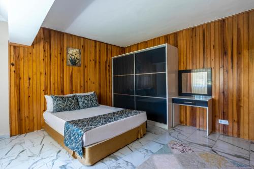um quarto com uma cama, uma televisão e paredes de madeira em AĞAOĞLU MY TERMAL 