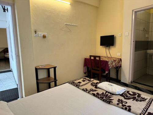 a room with a bed and a table and a television at Aambal Residency in Cochin