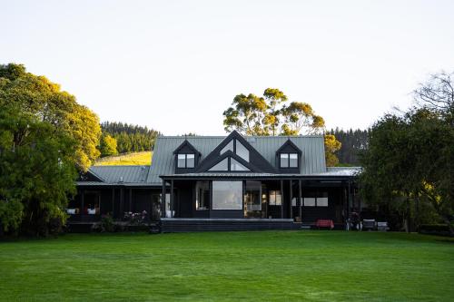 a house with a black roof on a green lawn at FOREST WATERS in Haruru