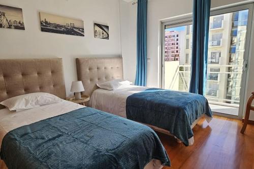 a bedroom with two beds and a large window at Vista Mar Concórdia by Rentallido in Funchal