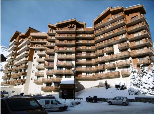 ein großes Apartmenthaus mit Autos im Schnee in der Unterkunft Cozy and Spectacular Condo VT in Val Thorens