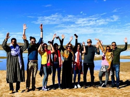 a group of people standing on the beach with their hands in the air at Aladdin merzouga camp in Merzouga