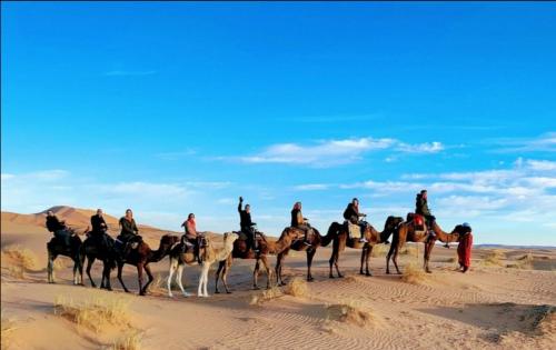 a group of people riding horses in the desert at Aladdin merzouga camp in Merzouga