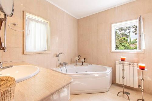 a white bathroom with a tub and a sink at Villa Alecrim in Aroeira