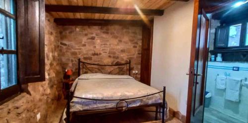 a small bed in a room with a stone wall at Alghero - Grotte di Nettuno cortes in Santa Maria la Palma
