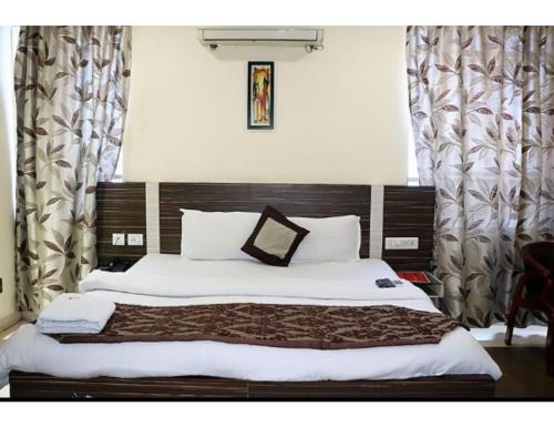 una camera con un grande letto con testiera in legno di Hotel Swayam, Jabalpur a Jabalpur
