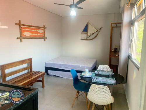 カラグアタトゥーバにあるLindo Flat com Ar Perto do Marのベッド、テーブル、椅子が備わる小さな客室です。