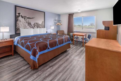 a hotel room with a bed and a desk at Super 8 by Wyndham Clayton in Clayton