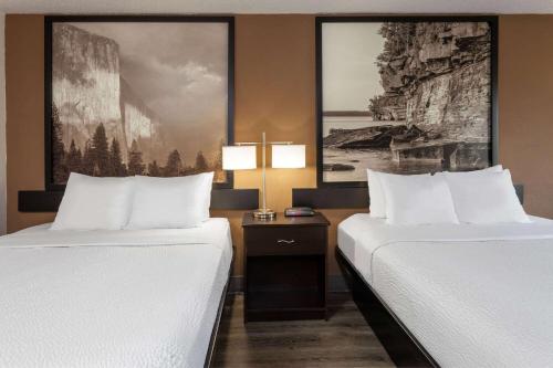 two beds in a hotel room with white sheets at Super 8 by Wyndham Wausau in Wausau