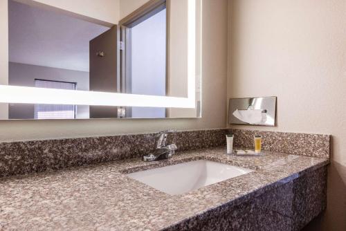 La salle de bains est pourvue d'un lavabo et d'un grand miroir. dans l'établissement Days Inn by Wyndham Mooresville Lake Norman, à Mooresville