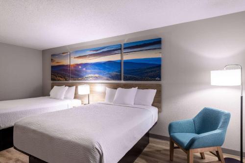 a hotel room with two beds and a blue chair at Days Inn by Wyndham Mooresville Lake Norman in Mooresville