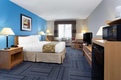 ein Hotelzimmer mit einem Bett und einem Flachbild-TV in der Unterkunft Baymont by Wyndham Marinette in Marinette