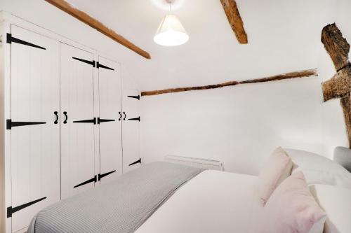 um quarto branco com uma cama e armários brancos em Perfectly Presented Cottage Pass the Keys em Robertsbridge