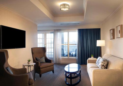 a living room with a couch and chairs and a tv at Hilton Alexandria Old Town in Alexandria