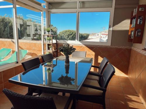 uma mesa de vidro e cadeiras num quarto com janelas em Apartamentos Maria em Málaga