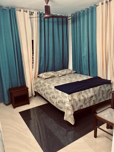 Bett in einem Zimmer mit blauen Vorhängen in der Unterkunft Puthookkadans Mareena Lodge in Kottayam