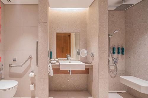 a bathroom with a sink and a shower and a toilet at Hilton Mauritius Resort & Spa in Flic-en-Flac