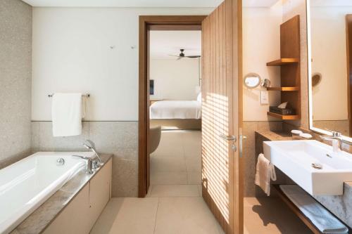 a bathroom with a bath tub and a sink and a bath tub at Hilton Mauritius Resort & Spa in Flic-en-Flac