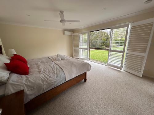 a bedroom with a bed with red pillows and a large window at Gardens by the Bay - Acreage Living & EV Charging in Deception Bay