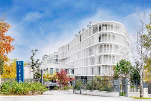 een kantoorgebouw met een bord erop bij GOLDEN TULIP LYON OUEST TECHLID Hotel & Spa in Limonest