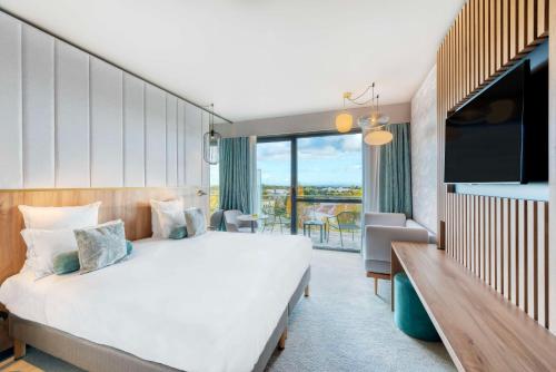 een hotelkamer met een groot bed en een televisie bij GOLDEN TULIP LYON OUEST TECHLID Hotel & Spa in Limonest