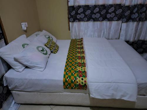 a bed with two pillows and a tie on it at Kangaroo Pouch Beach Resort in Busua