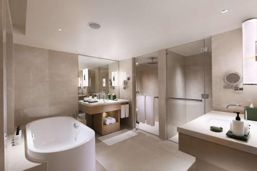 ein Badezimmer mit einer Badewanne, einem WC und einem Waschbecken in der Unterkunft Conrad Singapore Orchard in Singapur