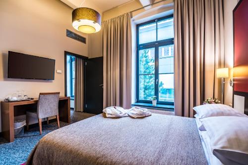 a hotel room with a bed and a desk and a television at VICTORIA Hotel Kaunas in Kaunas