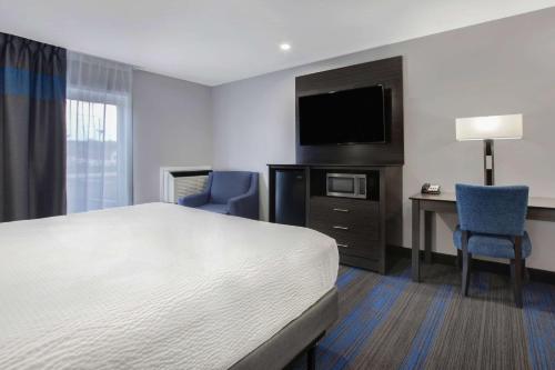 um quarto de hotel com uma cama, uma secretária e uma televisão em Days Inn by Wyndham Barrie em Barrie