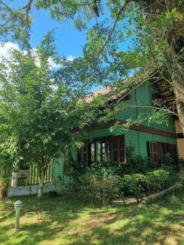 een groen huis met een boom ervoor bij Chalé Carvalho - Verde in Itapoa