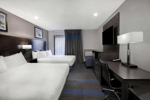 a hotel room with two beds and a desk at Days Inn by Wyndham Barrie in Barrie
