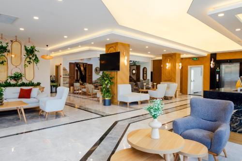 a lobby with chairs and tables and a tv at Güllük Elegance Otel in Gulluk