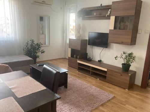 een woonkamer met een flatscreen-tv en een tafel bij Alacaster G apartman in Novi Sad