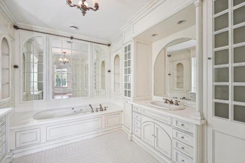 a white bathroom with two sinks and a tub at Villa Laval Bord de l'eau in Laval