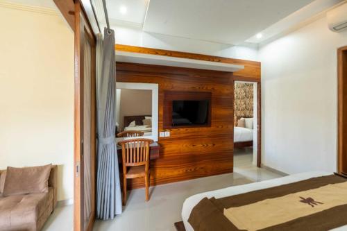 sypialnia z łóżkiem, kanapą i telewizorem w obiekcie The Yogasari Sanur w mieście Sanur