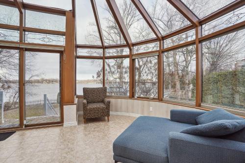 a conservatory with a couch and a chair and windows at Villa Laval Bord de l'eau in Laval