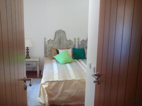 a bedroom with a bed with green pillows at Quinta dos Tesouros in São Brás de Alportel