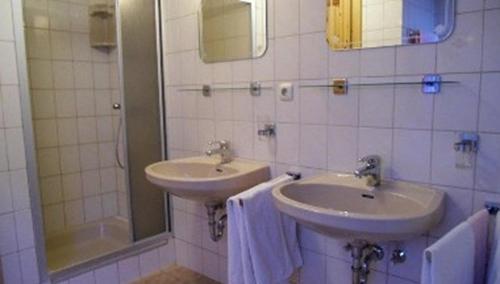 uma casa de banho com 2 lavatórios e um chuveiro em Gästehaus Erlhof em Schiefling am See