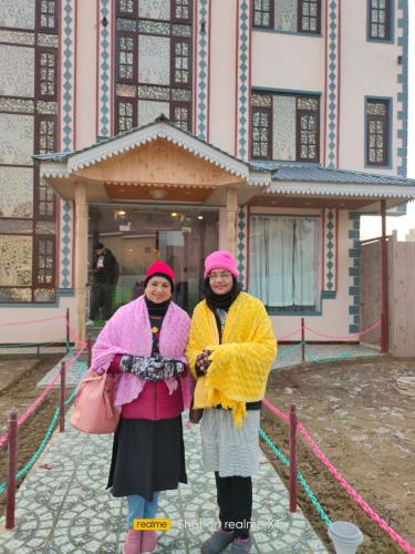 zwei Frauen stehen vor einem Gebäude in der Unterkunft Golden Eye in Srinagar