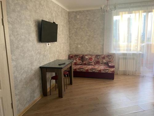 ein Wohnzimmer mit einem Tisch und einem Sofa in der Unterkunft Евродвушка в новостройке in Qaraghandy