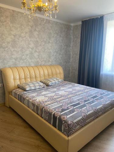 ein großes Bett in einem Schlafzimmer mit einem Kronleuchter in der Unterkunft Евродвушка в новостройке in Qaraghandy