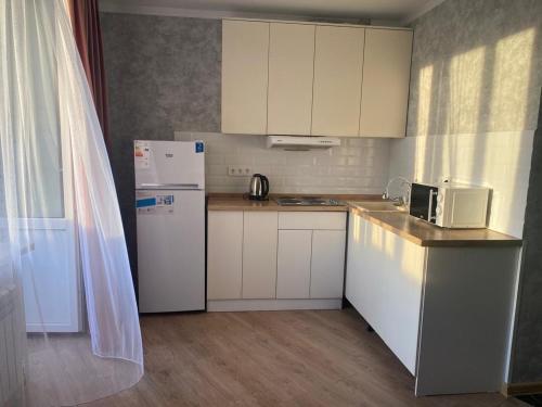 eine kleine Küche mit weißen Schränken und einem Kühlschrank in der Unterkunft Евродвушка в новостройке in Qaraghandy