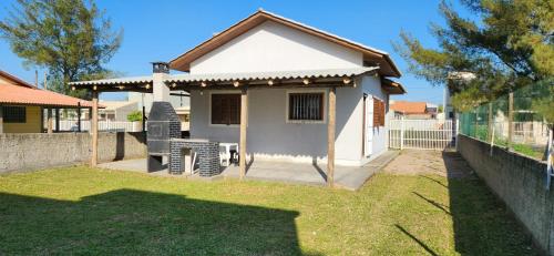 una pequeña casa blanca con una valla en casa Jardim ultramar 100mts do mar, en Balneário Gaivotas