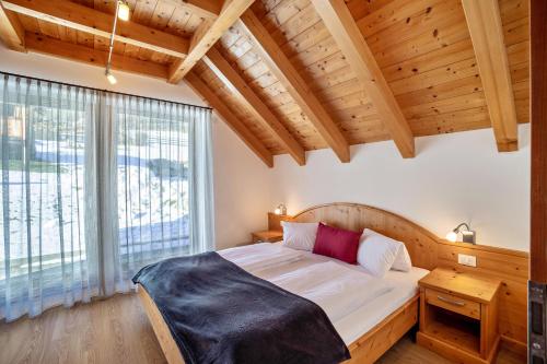 sypialnia z łóżkiem i dużym oknem w obiekcie Apartments Perfila Ferienchalet w mieście Valdaora