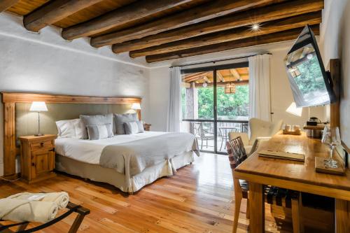 a bedroom with a bed and a desk and a television at Lares De Chacras in Chacras de Coria