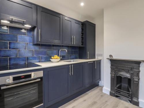 a kitchen with dark blue cabinets and a fireplace at Sally in Whitstable
