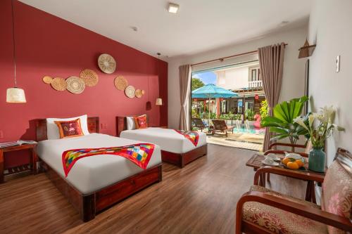 2 camas en una habitación con paredes rojas en Seagull Nest Hoi An Beach Village en Tân Thành (1)