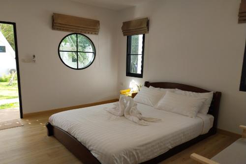 a bedroom with a bed with white sheets and a window at It my life cafe x camp in Ban Tha Sai