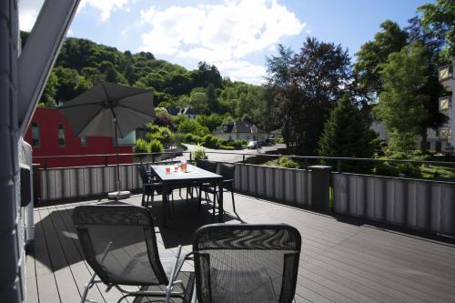 a patio with two chairs and a table and an umbrella at Haus Alleegarten in Bad Bertrich
