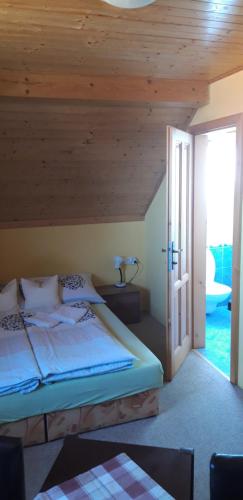 a bedroom with a bed with a wooden ceiling at Penzion U Štoly in Úsilné